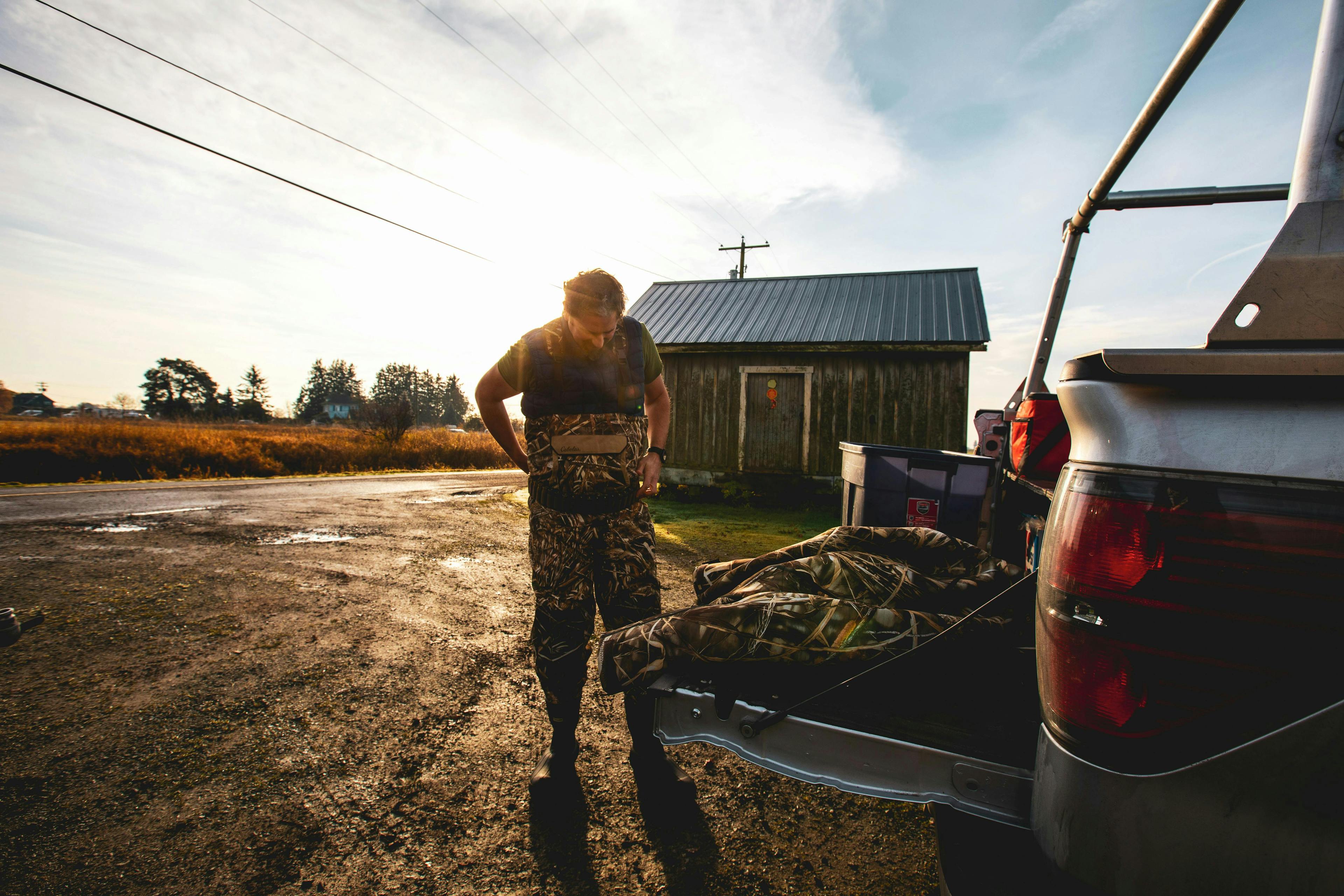 A person putting on hunting gear next to a truck tailgate